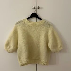 Gul stickad tröja - Mysig gul stickad tröja med korta ärmar och rund hals. Perfekt för kyliga dagar när du vill ha något bekvämt och stilrent. Passar bra till jeans eller kjol för en avslappnad look.