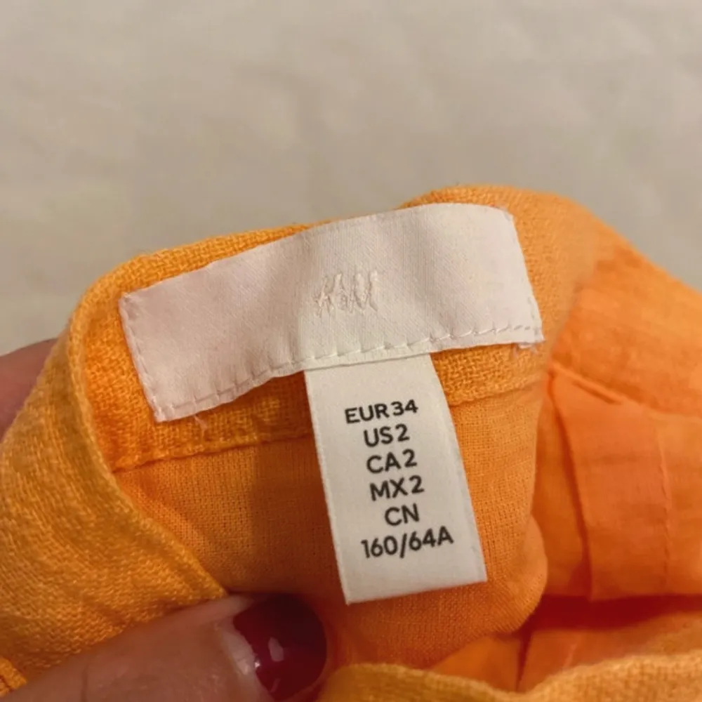 Säljer en snygg orange kjol från H&M i storlek XS. Kjolen har en cool rynkad detalj framtill och är gjord i ett lätt och luftigt material, perfekt för varma dagar. Den har en dragkedja baktill för enkel påklädning. Passar perfekt för en somrig look! 🍊. Hameet.