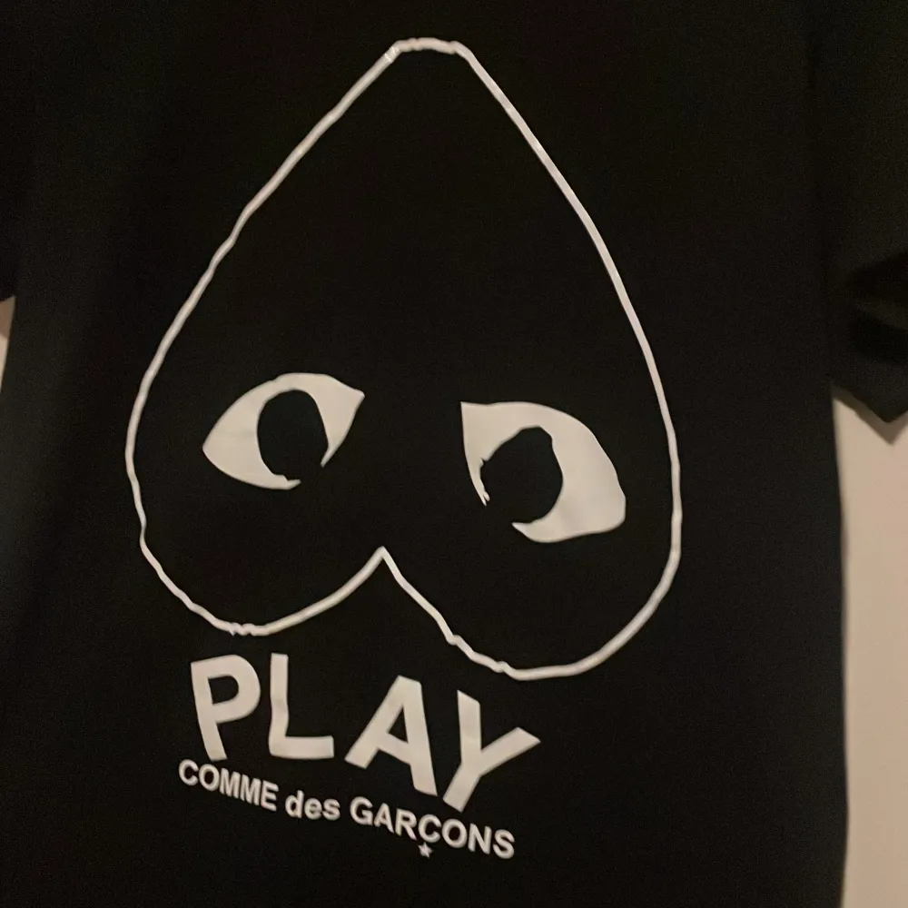 Snygg svart t-shirt från Comme des Garçons med det ikoniska hjärtmotivet och texten 'PLAY' på framsidan. Perfekt för en stilren och modern look. Skick 10/10 i princip oanvänd, bara testad.. T-paidat.