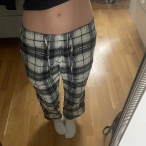 Rutiga pyjamasbyxor  - Säljer ett par bekväma pyjamasbyxor med svart, vit och grått mönster. Byxorna har en avslappnad passform och är väldigt bekväma!
