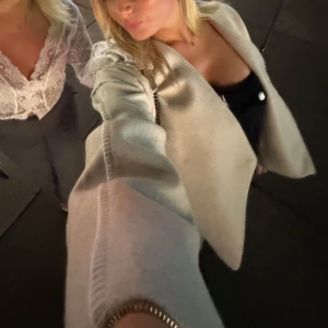 Beige kappa med knappar - Snygg beige kappa med knappar framtill. Perfekt för en stilren look. Jackan har en elegant design och passar bra till olika outfits.