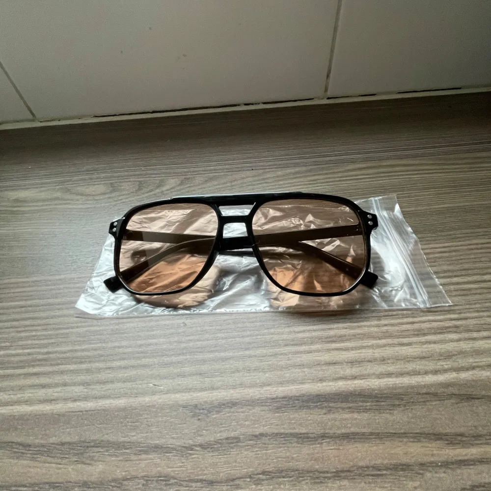 Coola svarta solglasögon med en klassisk aviator-stil. De har bruna tonade linser som ger ett stilrent intryck. Perfekta för en solig dag och ger en tidlös look.. Asusteet.