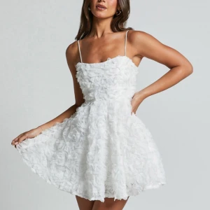 Vit klänning - Säljer en fantastisk vit studentklänning från Showpo med ett unikt blommigt 3D mönster. Klänningen har smala axelband som går att justera. Klänningen sitter tajt vid bysten och blir flowy vid midjan. Perfekt för student eller skolavslutning!🌸🤍Aldrig använd då den är för liten för mig!! Köptes för 900kr. 