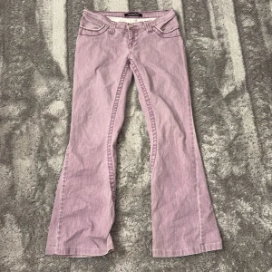 Lågmidjade bootcut jeans - Snygga lila bootcut jeans med låg midja och klassiska femficksdesign. Byxorna har dekorativa sömmar och knappar på bakfickorna.  De är tyvärr för små för mig därav säljer jag.☺️