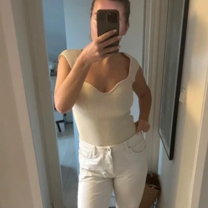 Stickad top - Säljer en stilren vit stickad topp med djup rund halsringning. Perfekt för varma dagar och lätt att matcha med olika outfits.
