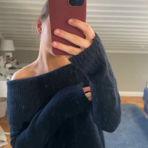Mörkblå offshoulder stickad tröja - Säljer en mysig mörkblå stickad tröja med offshoulder-design. Perfekt för kyliga dagar när du vill ha något bekvämt och stilrent. Tröjan har långa ärmar och en avslappnad passform. Passar perfekt till jeans eller kjol.
