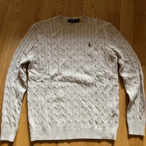 Polo stickad tröja - en helt oanvänd Stickad tröja från märket Polo Ralph Lauren i färgen beige. Storlek M