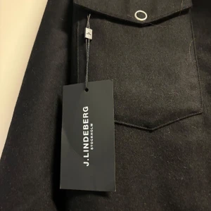 Svart jacka från J.Lindeberg - Snygg svart jacka från J.Lindeberg  med  knappar. Perfekt nu inför våren!