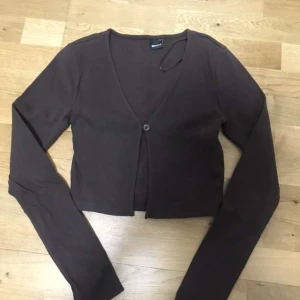 Brun croppad kofta - Säljer en stilren brun croppad kofta med en enkel knapp framtill. Den är dock lite liten för sin storlek.