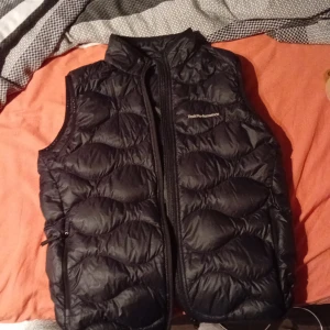 Svart dunväst från Peak Performance - Säljer en svart dunväst från Peak Performance. Västen har en dragkedja framtill och är quiltad för extra värme. Perfekt för vår dagarna som kommer och lite kyligare väder.Bra skick.kan gå ner i pris vid snabb affär