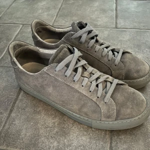 Grå mockasneakers från Garment Project - Mocka skor från garment project, ganska slitna + ett skosnöre är av så de kan användas som laceless. Storlek 42 men passar mig med 43. För mer frågor eller bilder är det bara att höra av sig. Allt gott!