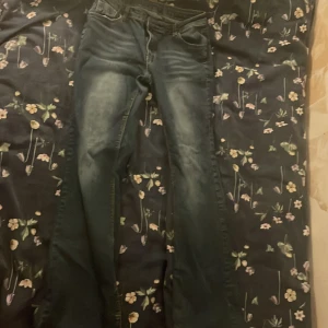 Mörkblå jeans med slitna benslut - Säljer ett par mörkblå jeans med snyggt slitna benslut och lätt tvättade detaljer framtill. Klassisk femficksmodell med utsvängda ben och normal passform. Perfekta för dig som gillar en avslappnad och tidlös look.