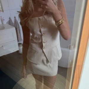 Zara set - Supersnygg beige kort klänning med knappar framtill och fickdetaljer. Axelbandslös modell som ger en clean och chic look. Perfekt för dig som gillar minimalistisk stil och vill sticka ut med en unik design.