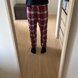 Rödrutiga mjukisbyxor med snörning - Säljer ett par sköna mjukisbyxor i röd, vit och svart rutig design. Byxorna är tillverkade i mjukt bomullstyg. Perfekta för chill dagar hemma eller när du vill vara extra bekväm.🥰