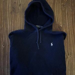 Mörkblå hoodie från Polo Ralph Lauren - Säljer en snygg mörkblå hoodie från Polo Ralph Lauren. Den är i ett stickat material och har en klassisk passform med långa ärmar och en praktisk huva med dragsko. Perfekt för kyliga dagar och avslappnade stunder. Den ikoniska loggan är broderad på bröstet. Passar både till vardags och lite finare tillfällen. Storlek L, passar M mer. Vid frågor ev funderingar kom privat!