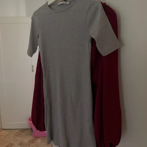 Grå ribbad kortklänning  - Säljer en enkel och stilren grå ribbad kortklänning från Lager 157. Klänningen har rund halsringning, korta ärmar och en tight passform som framhäver figuren. Perfekt att styla med sneakers eller boots för en clean look.