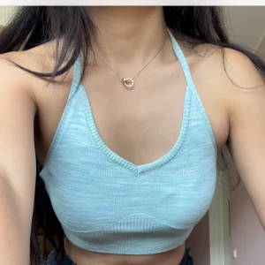 Ljusblå ribbad croppad linnetopp - Superfin ljusblå croppad linnetopp med ribbad struktur och v-ringning. Toppen har smala axelband som knyts i nacken och är ärmlös, perfekt för varma dagar. Mjuk och stretchig, passar snyggt till jeans eller kjol.