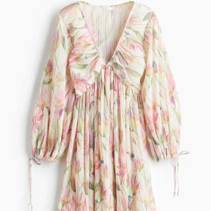 Populär blommig klänning från H&M - Klänningen har v-ringning, långa ärmar med knyt vid ärmslut och en flowy passform. Perfekt för sommarens alla tillfällen! Nyskick, nästan aldrig använd💗