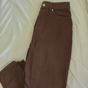 Bruna momjeans från H&M - Bruna jeans från H&M, Mom jeans! Byxorna är i stretchig bomullsblandning och har silverfärgade knappar. Normal i storlek!🌸
