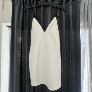 Vit kort klänning med svarta band - Jätte fin vit kort klänning från zara. Ca 80 cm lång. Rosettter på fram sidan och långa band bak till. I bra skick.