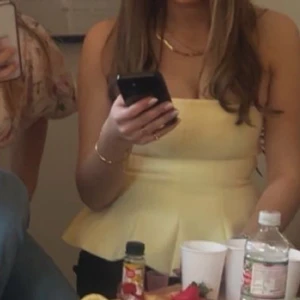 Gul axelbandslös bandeu top - Säljer en söt gul axelbandslös bandeu topp. Toppen har en figurnära passform upptill och volang nertill som ger en snygg siluett. 