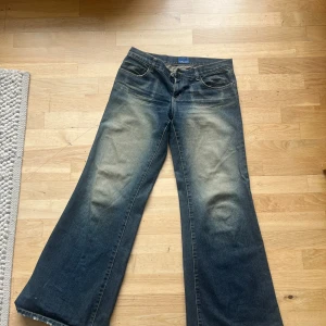 Roxy wide jeans med logga bak - Snygga blå jeans från Roxy med breda ben och coolt vit logga tryckt över bakfickorna. Jeansen har klassisk femficksdesign, låg midja och slitna detaljer för en avslappnad vibe. Perfekta för dig som gillar streetstyle och vill sticka ut.