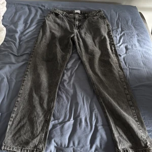 Grå jeans från Grunt i rak modell - Säljer ett par grå jeans från Grunt i rak passform. Jeansen är tillverkade i bomull och har klassisk femficksdesign med knapp och dragkedja. Snyggt tvättad grå färg som passar till det mesta. Märke och etikett syns tydligt i linningen.