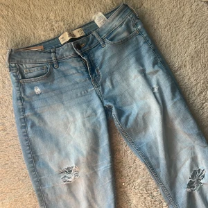 Jeans - Ljusblå jeans från Hollister med snygga slitningar och hål på benen. Free people liknande . Ifall man vill  ha bootcut kan man enkelt göra om dom då dessa är skinny men ass snygga🤩
