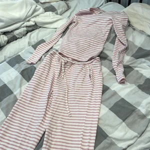 Randiga mjukisbyxor från Index XS - Supermysiga mjukisbyxor från Index i storlek XS, med rosa och vita ränder. Byxorna har dragsko i midjan och är tillverkade av ekologisk bomull. De har en loose passform och raka ben, perfekta för chill dagar hemma. Säljer som ett set 