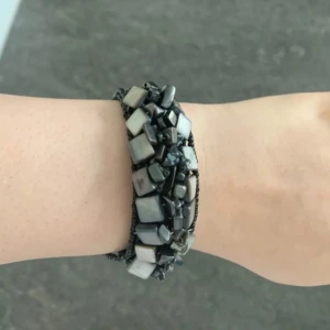 Svart pärlarmband med stenar - Unikt svart armband med flera rader små pärlor och stora fyrkantiga och oregelbundna stenar i svart och grått. Armbandet har en bred design och cool struktur som sticker ut på handleden. Perfekt accessoar för dig som gillar statement-smycken.