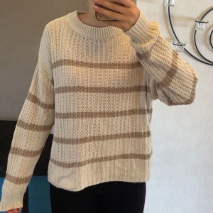 Randig stickad tröja  - Beige stickad tröja från 157 med breda, bruna ränder. Tröjan har en avslappnad passform, rund halsringning och långa ärmar. Inga slitage eller defekter! Storlek S men ganska stor så passar även M utan problem! Passar någon som brukar bära XS för en mer oversized look!🤎