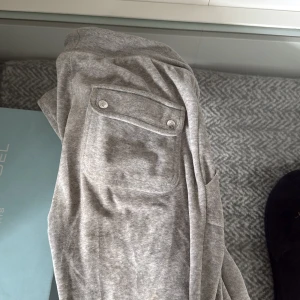 Juicy country  - Snygga grå mjukisbyxor i mjukt material med snörning i midjan och praktiska fickor fram och bak. Byxorna har en avslappnad passform och en liten broderad logga på ena benet. Perfekta för chill dagar eller när du vill vara bekväm. Juicy country 