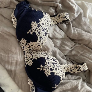 Mörkblå spets bh med blommor från intimissimi  - Supersnygg mörkblå bh med vit blommig spetsdetalj över hela kuporna och banden. Modell gioia i storlek 80C i fint skick. Nypris 520kr