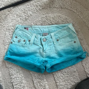 True Religion jeansshorts  - Snygga jeansshorts från True Religion i en turkos/blå ombré färg storlek W25, de är sparsamt använda och i mycket fint skick. Pris kan diskuteras! 