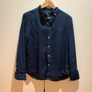 Ralph Lauren Skjorta - Säljer nu min sjukt snygga Ralph lauren linneskjorta i storlek 14-16 vilket motsvarar XS. Den är i jättefint skick och i mörkblå färg med en röd häst. hör av dig vid funderingar!