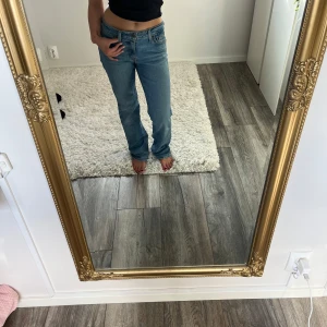 Levi's Superlow Boot jeans blå W26 L30 - Säljer ett par klassiska Levi's Superlow Boot jeans i ljusblå denim. Modellen har låg midja och bootcut-ben, perfekt för dig som gillar en avslappnad men ändå snygg look. Jeansen har fickor och ikonisk Levi's-lapp bak.
