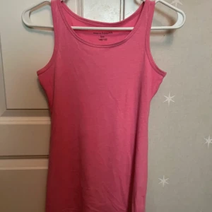 Rosa linnetopp från KappAhl - En enkel och snygg rosa linnetopp från KappAhl. Toppen är ärmlös med klassisk rund halsringning och har en rak passform. Perfekt att matcha med jeans eller shorts för en chill look.