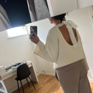 Vit stickad tröja med rosett i ryggen från ginatricot - Superfin oversized vit stickad tröja från ginatricot med bred ribbad struktur och stor, öppen rygg som knyts med en bred rosett. Tröjan har långärmade, lite vidare ärmar och en loose passform. Perfekt för dig som gillar unika detaljer och vill ha en mysig men snygg look.