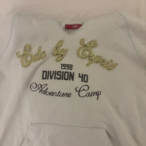 Vintage hoodie från Esprit med tryck - Ljusblå hoodie från Esprit med broderad och tryckt text på bröstet. Klassisk känguruficka framtill, huva och långa ärmar. Snygg casual stil med gul brodyr och svart text. Perfekt för chill dagar eller när du vill ha en avslappnad look. Den här hål vid fickan, som man kan se på bilden. Storleken är M men passar mer som S.