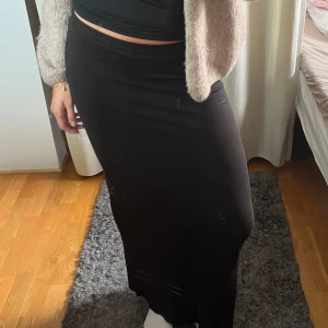 Svart långkjol i mjukt material - Säljer en svart långkjol med enkel och stilren design. Kjolen har en rak passform och är gjord i ett mjukt, stretchigt material som sitter bekvämt på kroppen.  Aldrig använd!