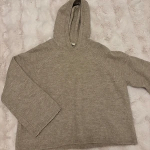 Beige stickad hoodie från Gina Tricot - Mysig beige stickad hoodie från Gina Tricot i storlek XS. Tröjan har en huva och långa ärmar med ribbade muddar. Perfekt för chill dagar och när du vill ha det extra bekvämt. Enkel och stilren design som funkar till allt.