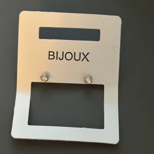 Silvriga örhängen med glittrande sten - Skickar iväg samma dag eller nästa🙌🏼Snygga små silvriga örhängen från Bijoux med rund form och glittrande klar sten i mitten. Perfekta för dig som gillar stilrena och diskreta smycken med lite extra bling. Säljs på originalkort.