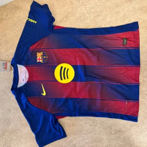 FC Barcelona Lamine Yamal matchtröja - Barça matchtröja med Lamine Yamal och nummer 10 på ryggen. Klassiska blå och röda ränder, gula detaljer och klubbmärke på bröstet. Nike-logga och Spotify-sponsor framtill, UNHCR-tryck bak. Tillverkad i lätt och ventilerande material.