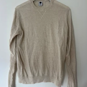 Beige tröja från NN07 i bomull/linne - Snygg beige tröja från NN07 i en skön mix av 70% bomull och 30% linne. Enkel och stilren design med rund halsringning och långa ärmar. Perfekt för dig som gillar en clean och avslappnad look.