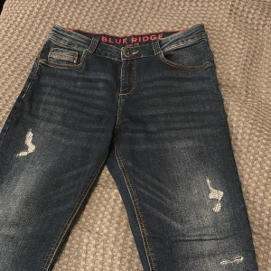 Blå jeans med slitningar från Blue Ridge - Säljer ett par tvättade slim fit jeans från Blue Ridge. Jeansen har små snygga slitningar på båda benen men inget hål igenom. Storleken är Slim 158 och passar nån från 150-165 lite beroende på hur man vill att de ska sitta och vikt. De är köpta på Zalando för något år sedan och är väl använda. ✅Kontakta mig om du undrar något! / Gustav 👊🏼😊