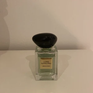 Armani Privé Cyprès Pantelleria parfym - Exklusiv parfym från Armani Privé, Cyprès Pantelleria. Flaskan är rektangulär i klart glas med ljusgrön vätska och har en unik, svart oval kork. Elegant guldig etikett framtill. Perfekt för dig som gillar lyxiga och stilrena dofter.