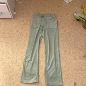 Mintgröna velourbyxor Juicy Couture XXS - Snygga mintgröna velourbyxor från Juicy Couture med broderad JC-logga framtill. Byxorna har bred resår i midjan med snörning, stora fickor fram och bak samt raka ben. Perfekta för en chill och trendig look. Priset kan diskuteras!