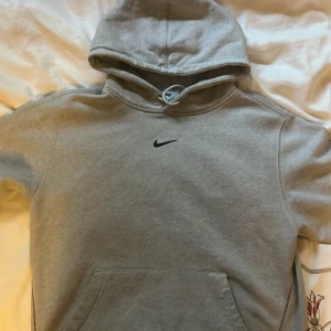 Nike x Drake NOCTA Cardinal Stock Grey Hoodie - Äkta grå Nocta Cardinal Stock Hoodie köpt 2021 från Trés Bien Sweden. Storlek M. Mycket bra skick då jag knappt har användt tröjan! 