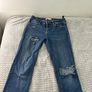 Blå s jeans från Zara - Säljer ett par blå jeans från Zara med snygga slitningar och hål på benen för en cool, avslappnad look. Jeansen har 4st håll vid benen men de går att sy up de. Priset går alltid att dusketera 😊💕