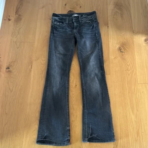Mörkgrå bootcut jeans Gina Tricot - Snygga mörkgrå jeans från Gina Tricot i bootcut-modell. Jeansen har klassisk femficksdesign, hög midja och lätt slitna detaljer för en cool look. Perfekta till sneakers eller boots och passar dig som gillar en tidlös stil.